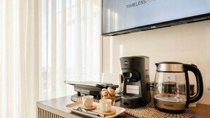 Habitación de hotel con espacio para café, televisión y ventana con cortinas.