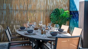 A round dining table set with chairs, surrounded by a bamboo fence and a large plant. - Casa Tortuga – Luxury Holiday Home in Papaya Hill Resort, Cu (Grote Berg)