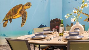 A dining table set with blue and white plates, bowls, and cutlery, a vase with flowers, and a bottle of wine. - Casa Tortuga – Luxury Holiday Home in Papaya Hill Resort, Cu (Grote Berg)