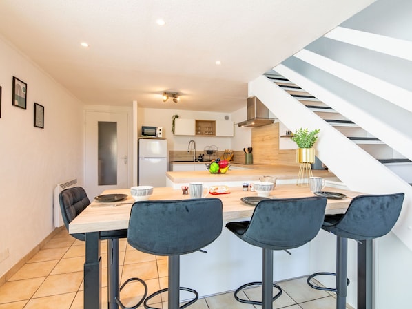A modern kitchen with a central island, bar stools, and a staircase.