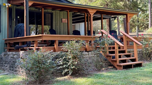 A rustic cabin with a wooden deck and a covered porch.