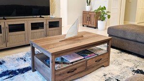 Un salon avec une table basse en bois, un téléviseur à écran plat, un canapé et un meuble.