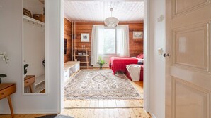 Ein gemütliches Schlafzimmer mit Holzbalkendecke, einem roten Bett und einem kleinen Fenster.