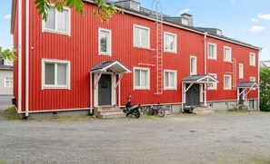 Un bâtiment rouge avec de nombreuses fenêtres et un petit porche. On peut voir des vélos garés devant.