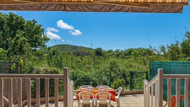 An outdoor dining area with a view of a lush garden and hills. - Les Mimosanes by Interhome (Bormes-les-Mimosas)