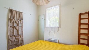 A bedroom with a bed, a window, a radiator, and a wooden ladder. - Les Mimosanes by Interhome (Bormes-les-Mimosas)