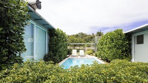 A swimming pool surrounded by lush greenery and a modern building with a blue exterior. - 3-bedroom 4 Bathrooms Solar Panels, Pool, Near Beaches, Vega Alta / Dorado (Vega Alta)