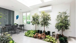 A modern interior with a dining area, large windows, and indoor plants. - 3-bedroom 4 Bathrooms Solar Panels, Pool, Near Beaches, Vega Alta / Dorado (Vega Alta)