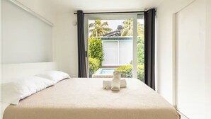 A hotel room with a bed, a window, and a view of a pool and greenery outside. - 3-bedroom 4 Bathrooms Solar Panels, Pool, Near Beaches, Vega Alta / Dorado (Vega Alta)