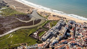 An aerial view of a coastal city with a beachfront, a river, and a dense urban area with modern buildings. - Bayline Algarve Apt – Beachfront, Spa, Lagoon View (Armação de Pêra)