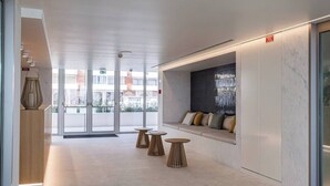 A modern lobby with a seating area, a reception desk, and a glass door entrance. - Bayline Algarve Apt – Beachfront, Spa, Lagoon View (Armação de Pêra)