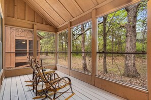 Une cabane en bois dotée de grandes fenêtres donnant sur une forêt.