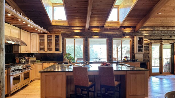 A spacious kitchen with a large island, wooden cabinets, and a stone countertop.