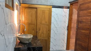 A bathroom with a marble sink, wooden vanity, and a toilet. - Ganayu Bali Villa (Gobleg)