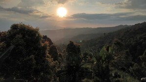 A landscape with a sun setting behind hills and dense vegetation. - Ganayu Bali Villa (Gobleg)