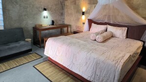 A bedroom with a bed, a nightstand, a bedside table, a lamp, and a sofa. - Ganayu Bali Villa (Gobleg)