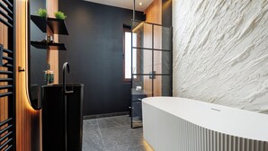 Un baño moderno con una paleta de colores blanco y negro, que incluye un espejo grande, un lavamanos blanco y una pared con textura.