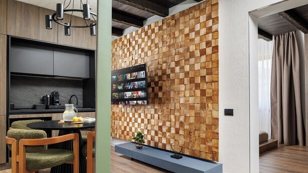 Una cocina moderna con televisor integrado, paneles de madera y un comedor con mesa y sillas.