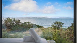 A view from a window overlooking a body of water with distant land and greenery.