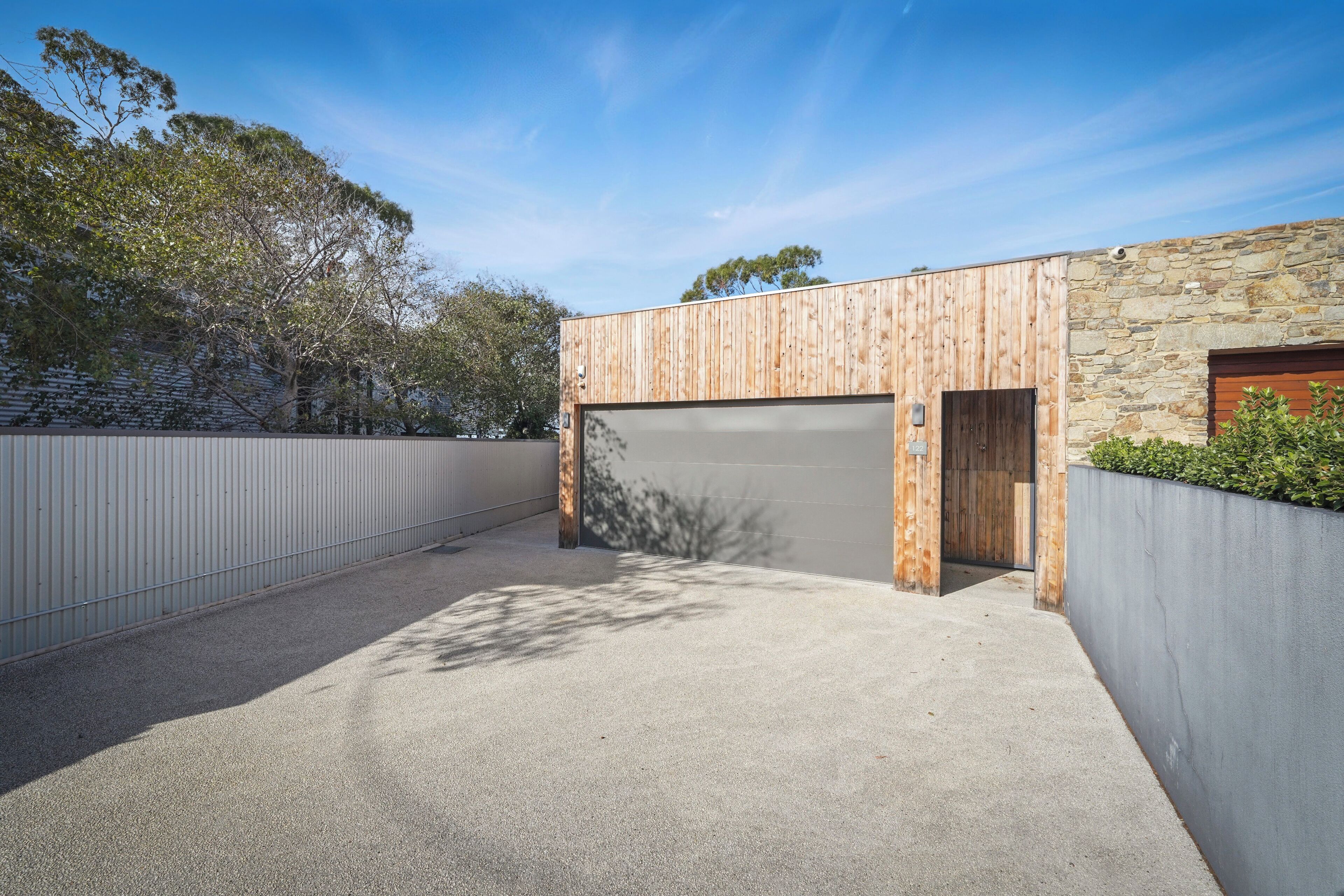 Een modern gebouw met garage, stenen muur en oprit van beton.