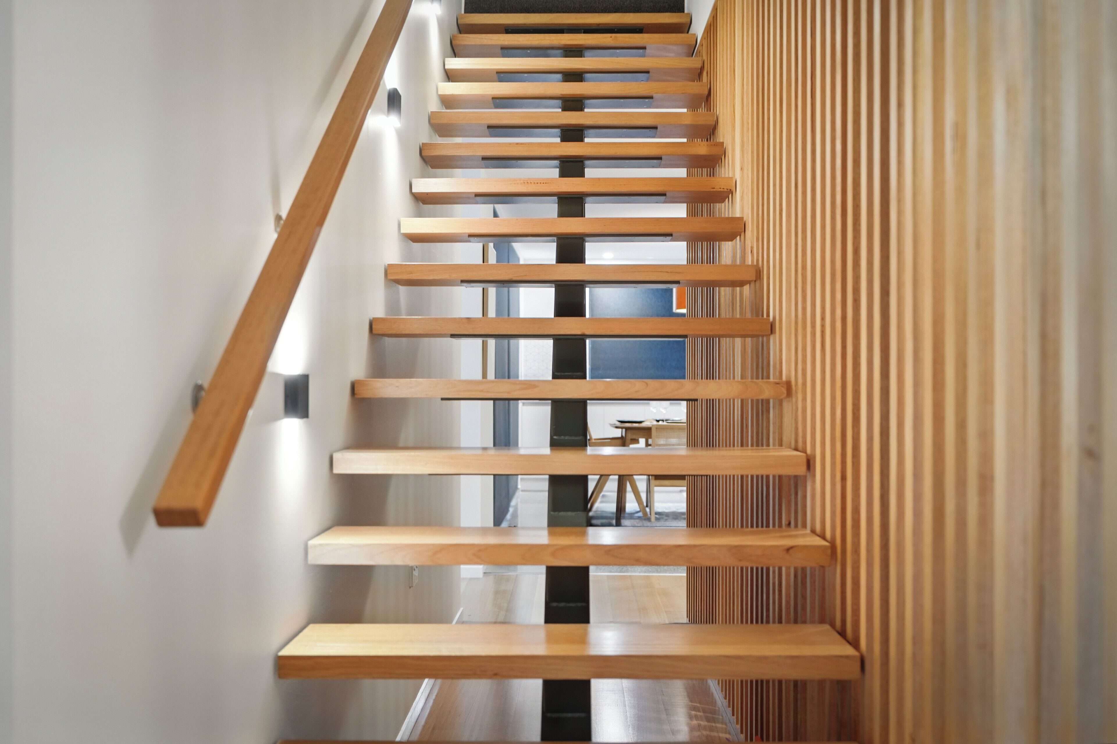 A modern staircase with wooden steps and a slatted wall design.