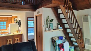 A spacious loft with a wooden staircase, a kitchen with wooden cabinets, and a cozy seating area.