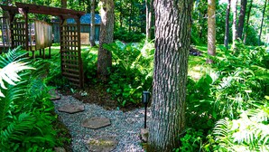 A garden pathway with stepping stones, surrounded by lush greenery and trees.