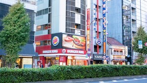Un restaurante Burger King con un letrero grande, rodeado de otros edificios y un árbol.