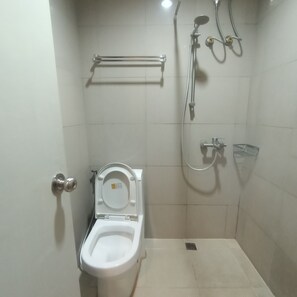 Une petite salle de bain moderne équipée de toilettes, d’une douche et d’un porte-serviettes.