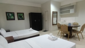 Ein Hotelzimmer mit zwei Einzelbetten, einem Schreibtisch mit Stuhl, einem Kleiderschrank und einem Spiegel an der Wand.