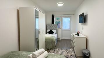 Una habitación de hotel moderna con dos camas, un escritorio, un televisor y un baño.