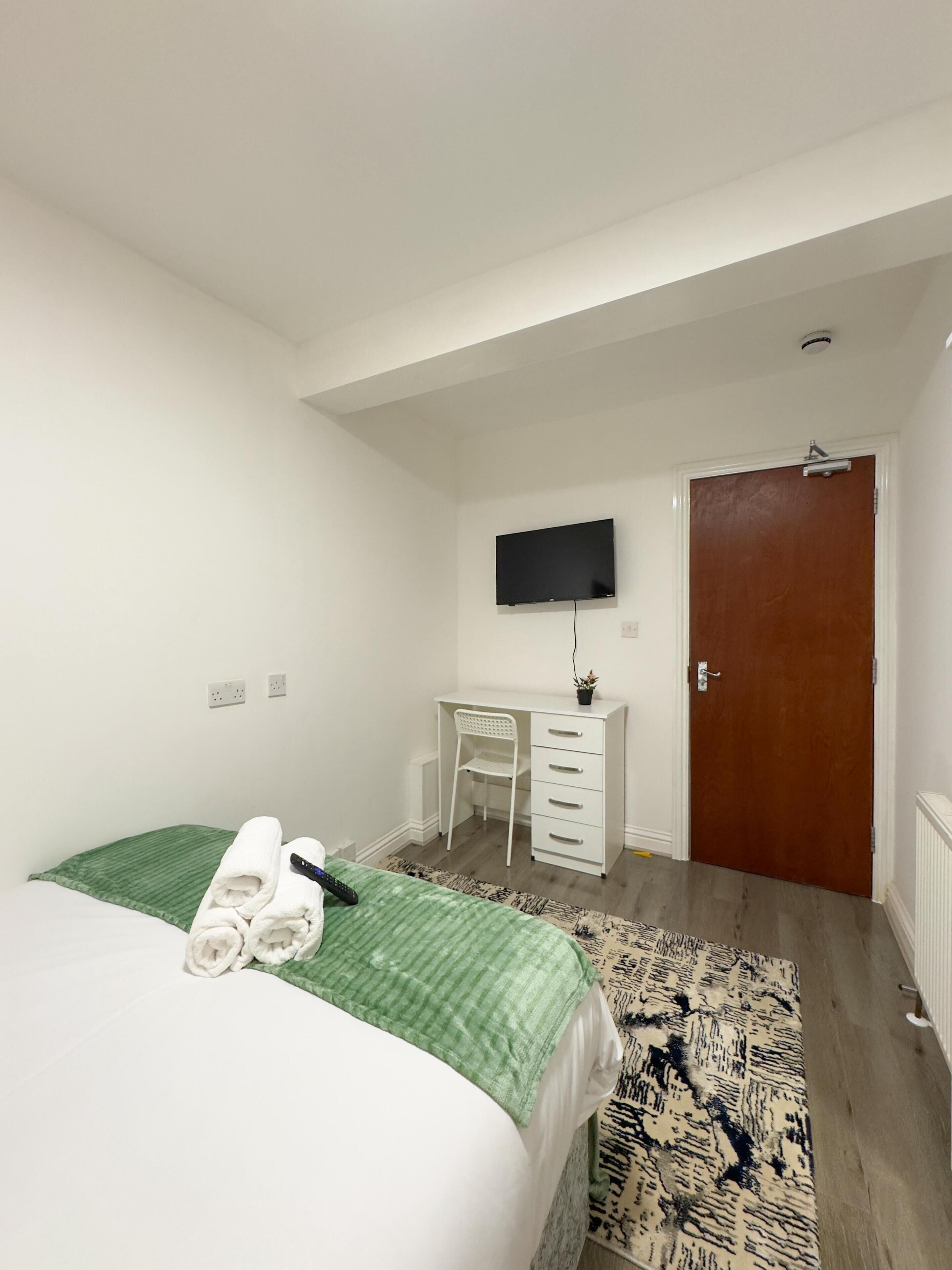 A hotel room with a bed, a desk, a television, and a door.