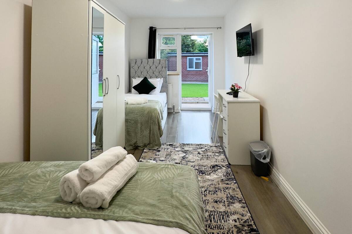 A modern bedroom with a bed, a wardrobe, a bedside table, a TV, and a view of the outside.