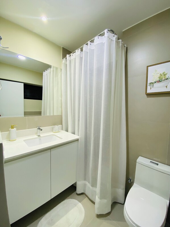 Un baño con lavabo, espejo e inodoro blanco.