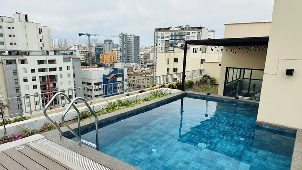 A rooftop pool with a city view, surrounded by buildings and a construction crane in the background. - Nephi’s Villas Modern 2 Bedroom Apartment with Pool, Gym. Miraflores Location (Miraflores)