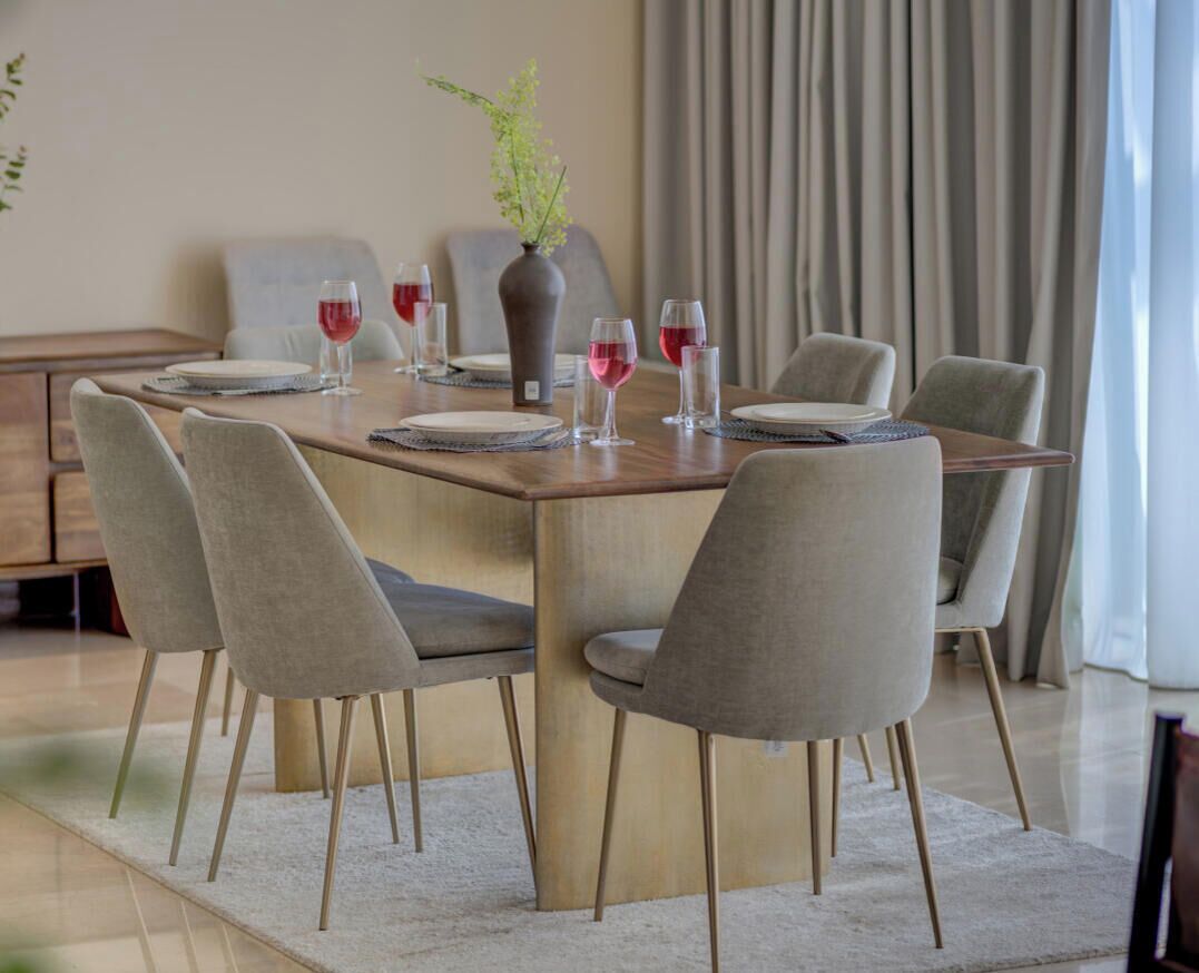 A dining area with a wooden table, six chairs, and a vase with flowers.