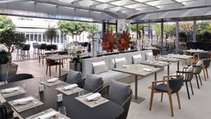 An outdoor dining area with tables and chairs, a sofa, and potted plants. - Elegant Studio|Panoramic Burj Views & Mall Access (Dubai)