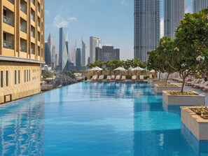 A swimming pool with lounge chairs and planters, surrounded by high-rise buildings.