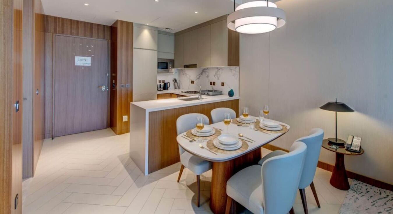 A modern dining area with a central island, light blue chairs, and a table set for four.
