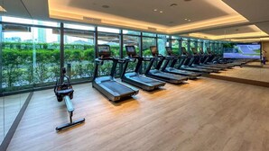 Un gimnasio moderno con cintas de correr, una máquina de remo y una pantalla de televisión grande.