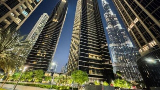 Vista nocturna de modernos edificios altos con ventanas iluminadas y cielo despejado.