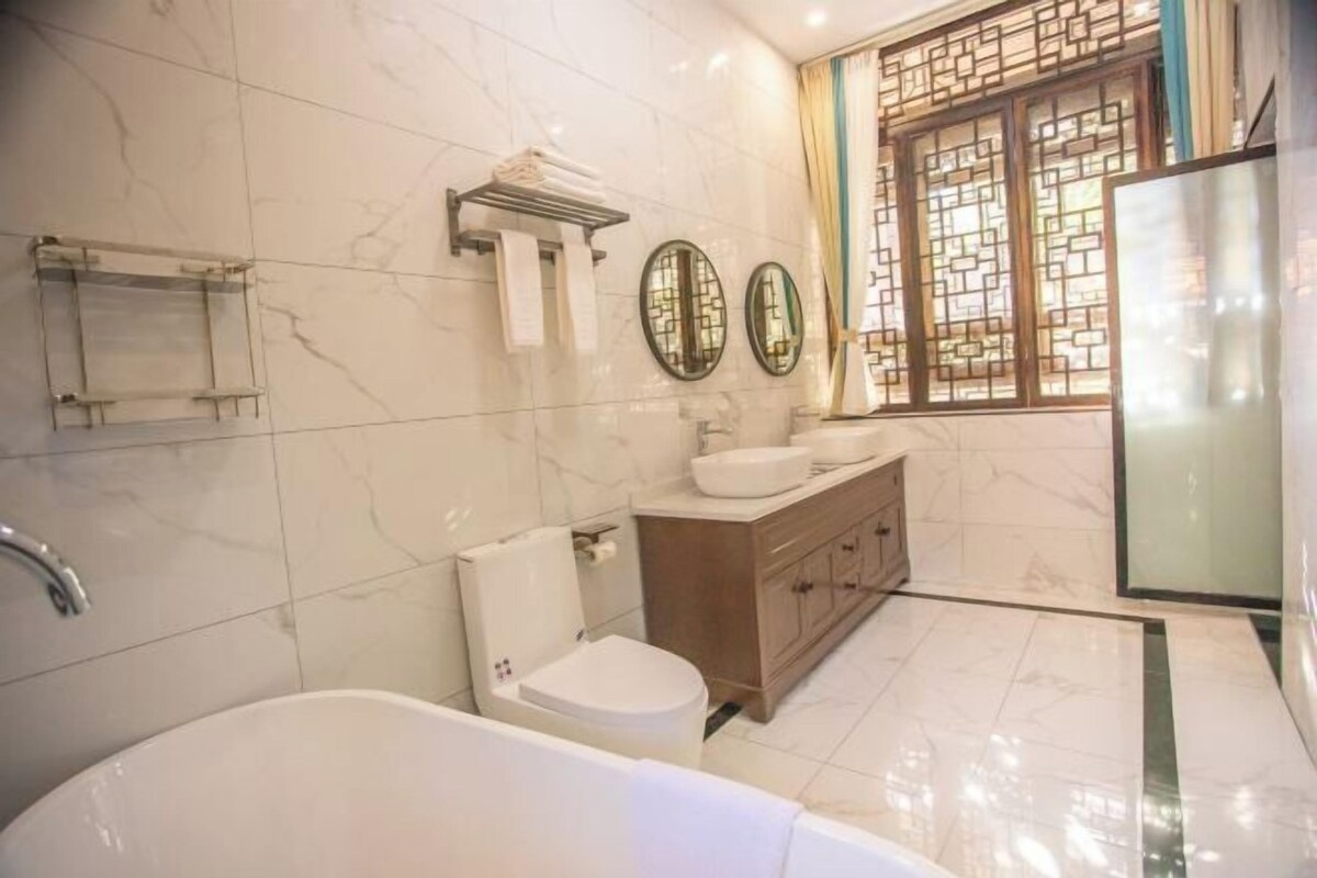 A modern bathroom with a bathtub, toilet, vanity, and two wall-mounted mirrors.