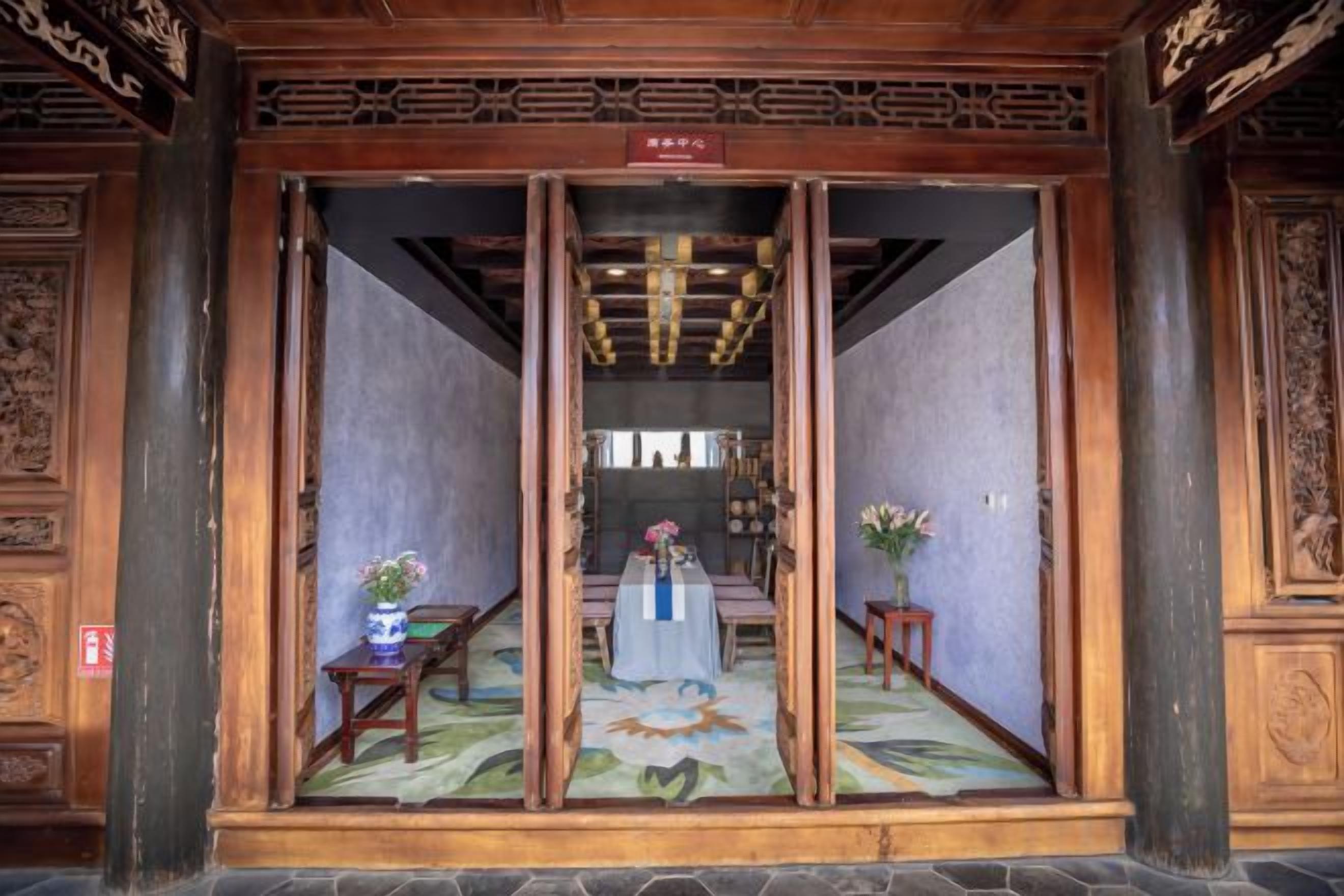 Une pièce de style traditionnel, avec une porte en bois, une table ornée d’un vase et un sol recouvert d’une moquette.