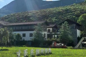 A traditional building with a sloped roof, surrounded by a grassy field and a mountainous backdrop. - Heqing Cunshi Manor · YouRan Residence (Heqing)