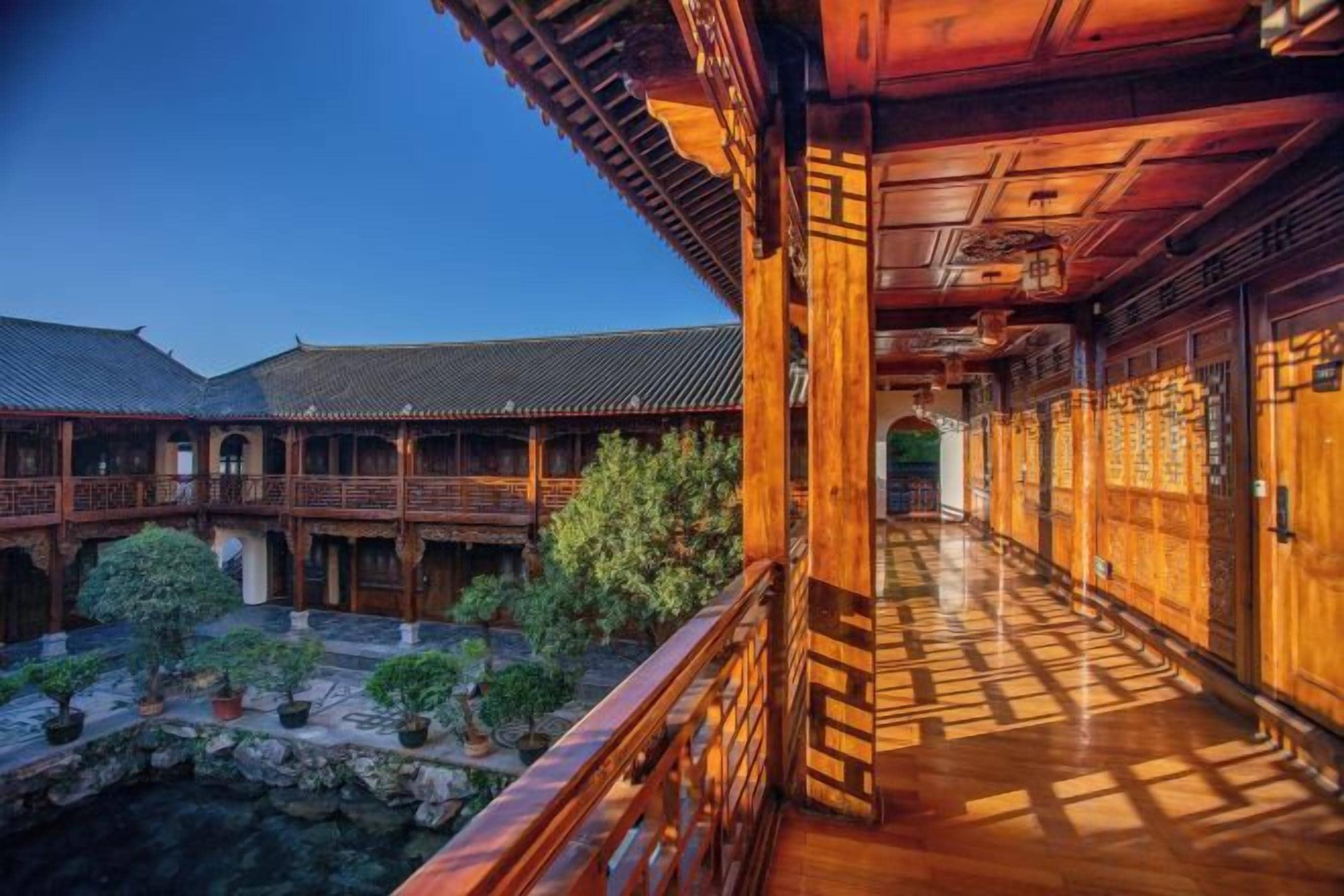 A traditional wooden building with a courtyard, wooden railings, and a stone pathway.