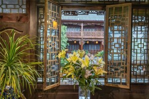 Un portón tradicional chino con vistas a un patio interior y una maceta con flores amarillas.
