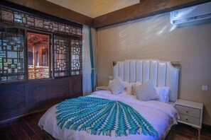 A bedroom with a bed, bedside table, and an air conditioning unit. - Heqing Cunshi Manor · YouRan Residence (Heqing)