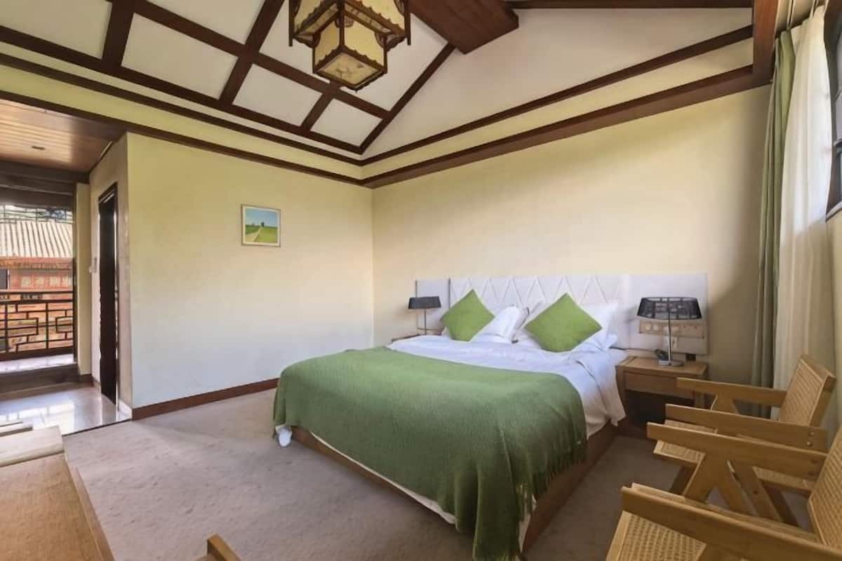 Un dormitorio con cama, mesitas de noche, una ventana y vistas al exterior.