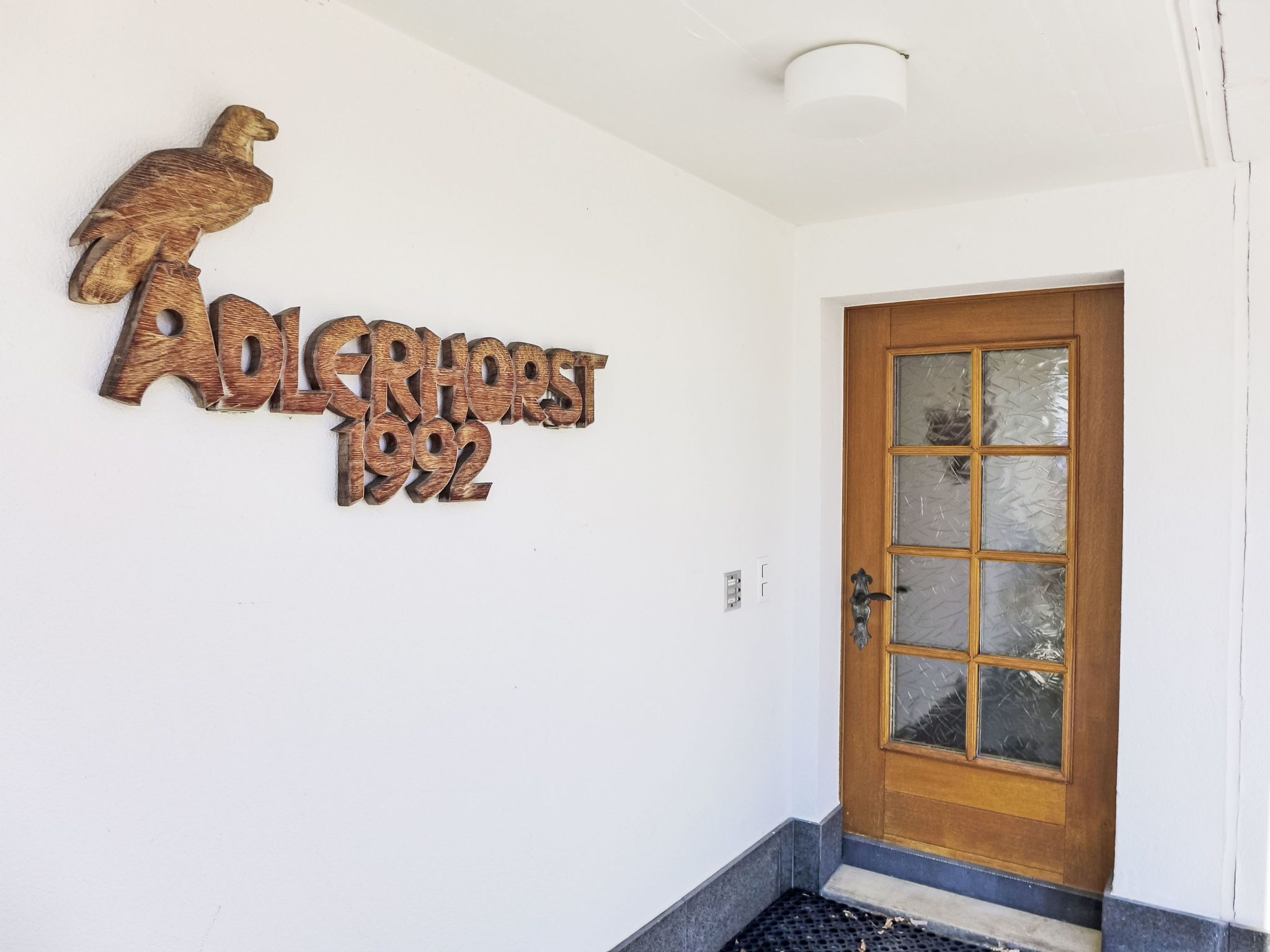 Une porte en bois avec un panneau en verre dépoli et un décor en métal représentant un aigle au-dessus.