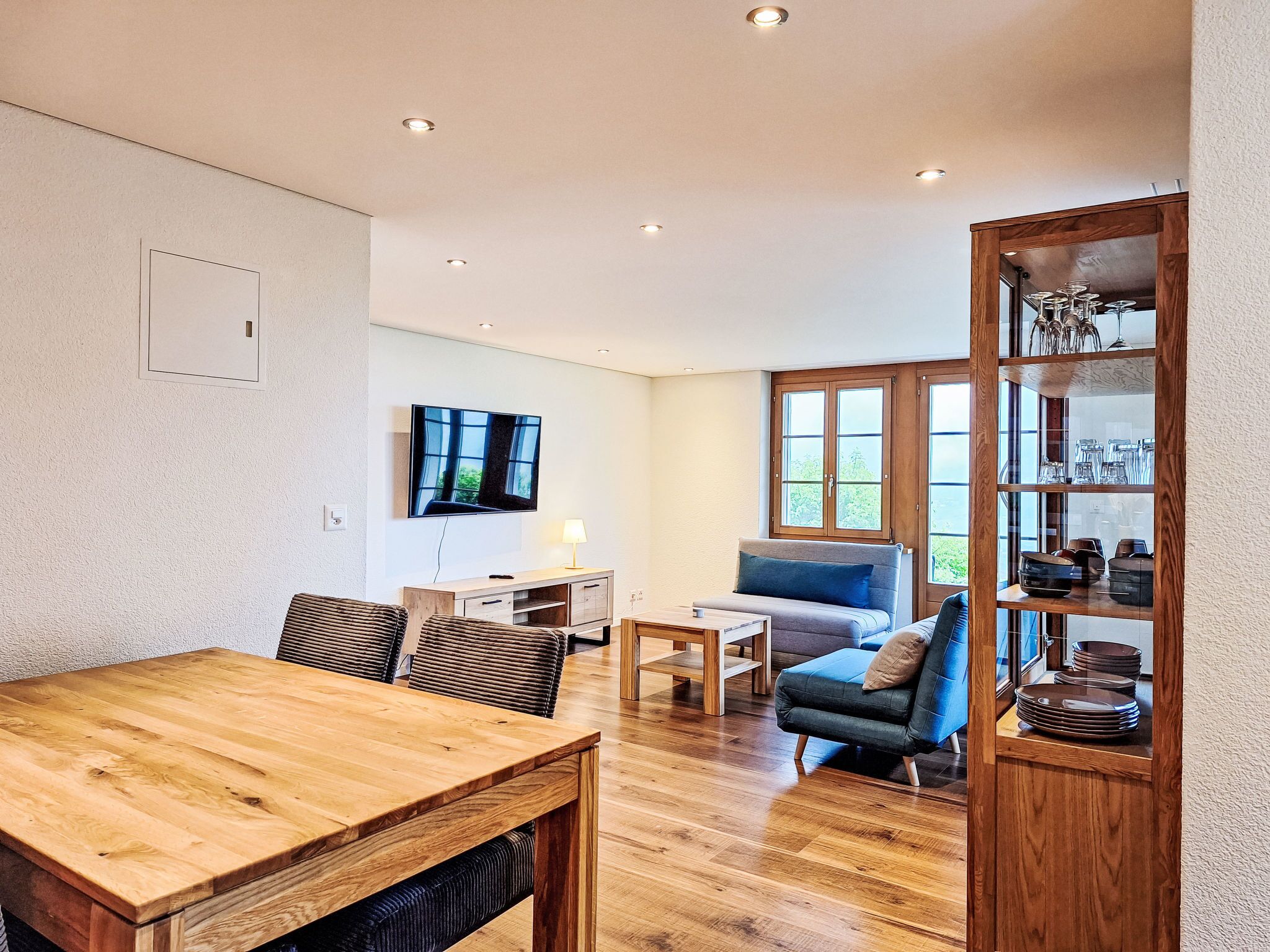 Un soggiorno moderno con un tavolo da pranzo in legno, un divano e una TV a parete.